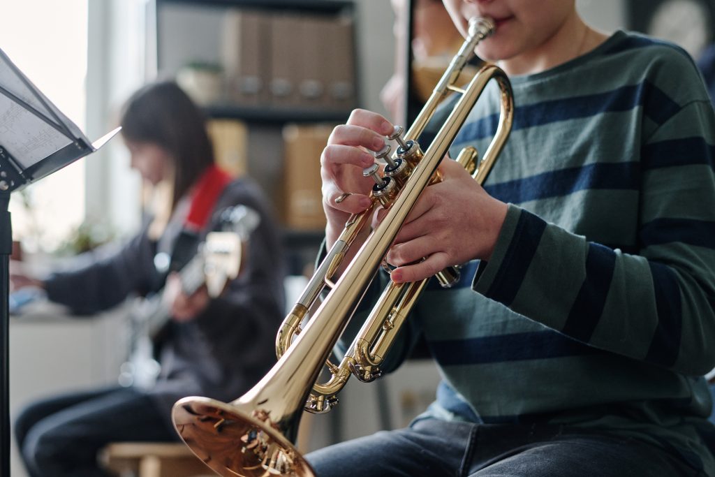 unrecognizable boy playing trumpet